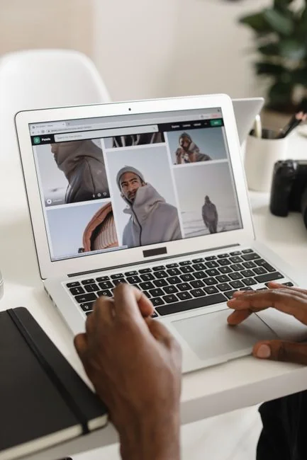 A modern workspace showing hands analyzing marketing data on a laptop and paper documents.